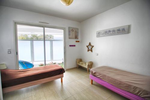 une chambre avec deux lits et une grande fenêtre dans l'établissement Appartement Les Rivages Calvi, à Calvi