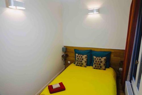 - une petite chambre avec un lit jaune et 2 oreillers dans l'établissement Profitez des Jeux Olympiques avec ce Magnifique appartement tout confort, à Neuilly-Plaisance