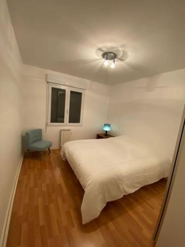 une chambre avec un lit blanc et une chaise bleue dans l'établissement Villa avec piscine près Hossegor Capbreton, à Angresse