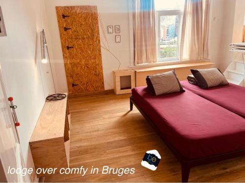 a room with a bed with a red comforter at be house in Bruges