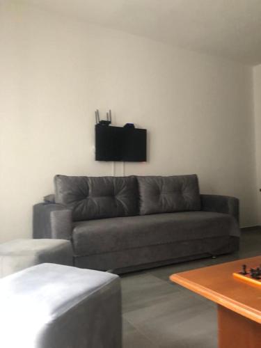 een woonkamer met een bank en een tv aan de muur bij Jurgen's Apartaments in Vlorë