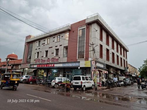 a busy city street with cars parked in front of a building at ANAND HOTEL in Bikaner