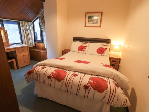 a bedroom with a bed with red flowers on it at 9 Camden Building in Kendal