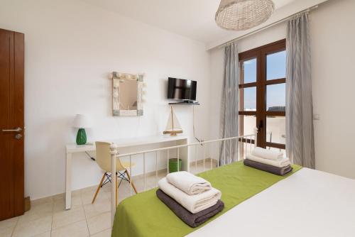 a bedroom with a bed and a desk and a window at Lindos Aeonian Villas in Líndos