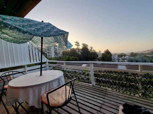 einen Tisch und Stühle auf einem Balkon mit Sonnenschirm in der Unterkunft Linda Casa 2D 1B in Viña del Mar