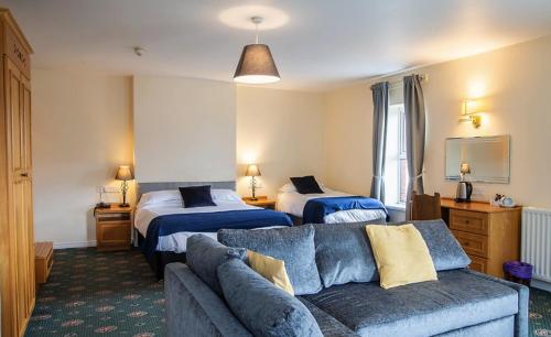 Habitación de hotel con 2 camas y sofá en The Donard Hotel en Newcastle