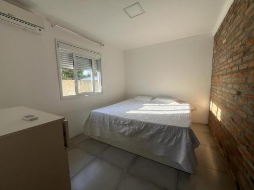 1 dormitorio con cama y pared de ladrillo en Casa com piscina em Torres, en Torres