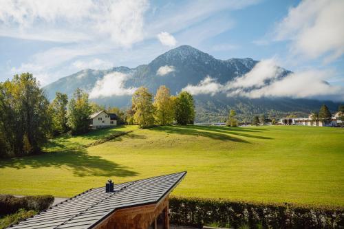 a house on a green field with mountains in the background at DAS SALZBERG Hideaway Bad Aussee - Adults only in Bad Aussee