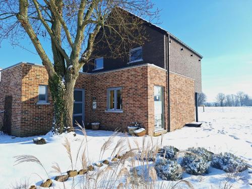a brick house in the snow with a tree at Côté Jardin in Buvrinnes