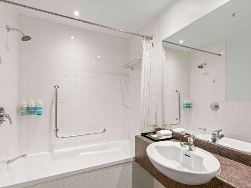 a white bathroom with a sink and a tub and a bath tub at Novotel Queenstown Lakeside in Queenstown