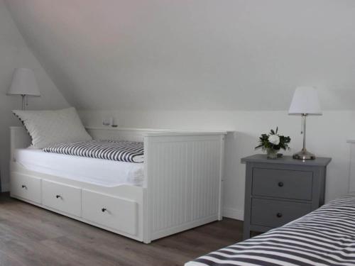 a white bedroom with a bed and a night stand at Cathedral day "Hygge" in Kronsgaard