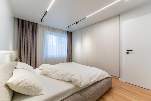 a bedroom with a white bed and a window at Kuib Central Apartament in Arad