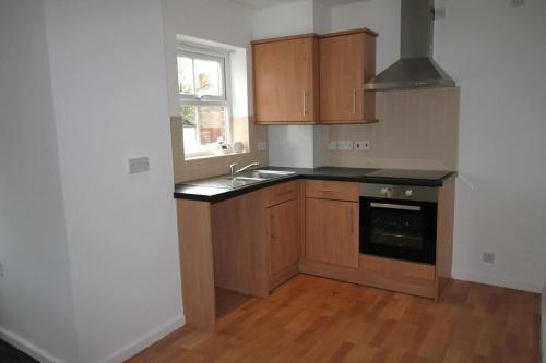 cocina con armarios de madera, fregadero y ventana en Arlington Court Apartment, en Washington