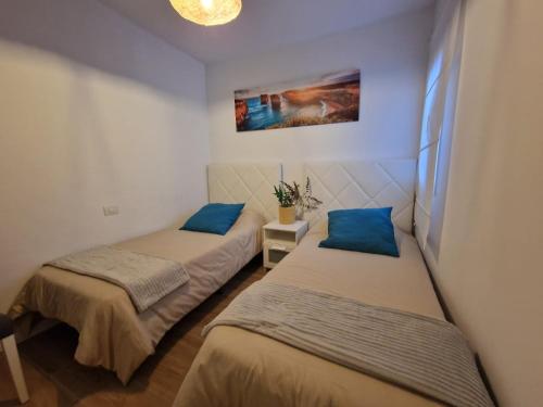 two beds in a small room with blue pillows at MALVASIA 5 in Famara