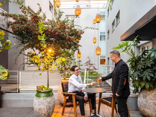 two men shaking hands at a table in a courtyard at ibis Paris Place d’Italie 13ème in Paris