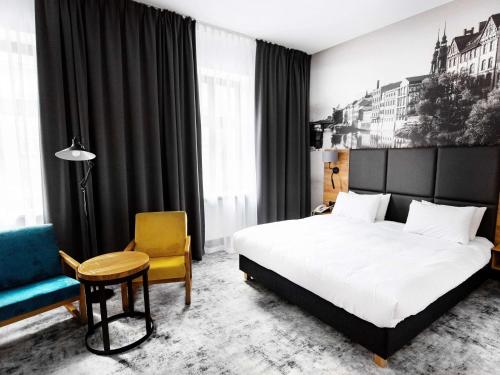 een hotelkamer met een bed en een stoel bij Mercure Opole in Opole