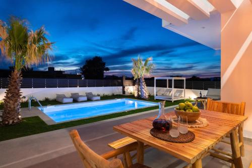a patio with a table and a swimming pool at Martinis Villas in Kremasti