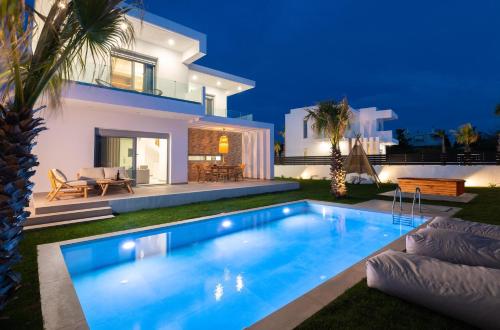 a villa with a swimming pool in front of a house at Martini Villas in Kremasti