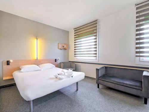 um quarto com uma grande cama branca e um sofá em ibis budget Katowice Centrum em Katowice