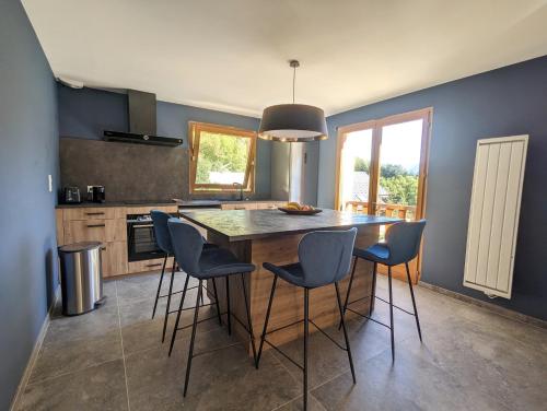 une cuisine avec un grand îlot en bois et des fauteuils de bar dans l'établissement Chalet Stella 5* à 2mn des pistes, à Saint-Chaffrey