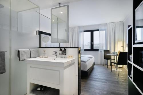ein weißes Bad mit einem Waschbecken und einem Bett in der Unterkunft INNSiDE by Meliá Hamburg Hafen in Hamburg