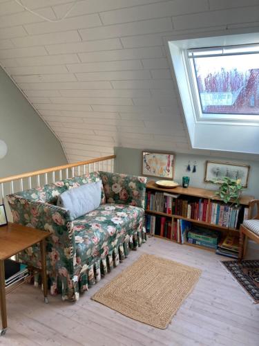 a living room with a couch and a book shelf at Lises bed and breakfast in Svendborg