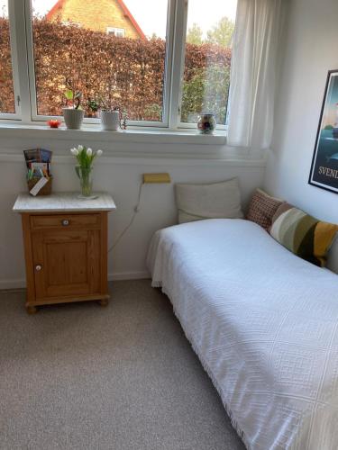 a bedroom with a bed and a table and windows at Lises bed and breakfast in Svendborg