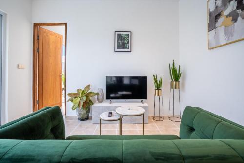 a living room with a green couch and a tv at Eden Cemagi Villa Pererenan in Canggu