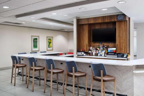 a bar in a room with chairs and a tv at Hilton Garden Inn Schaumburg in Schaumburg