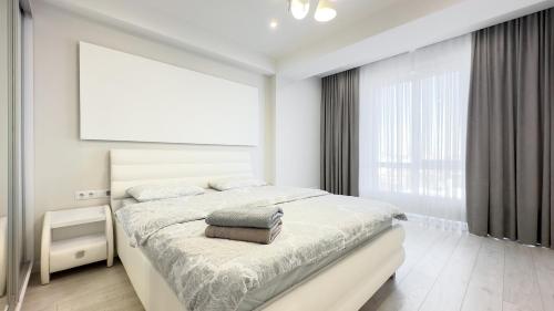 - une chambre blanche avec un lit et une grande fenêtre dans l'établissement Ismail Ultracentral Deluxe Apartaments, à Chişinău