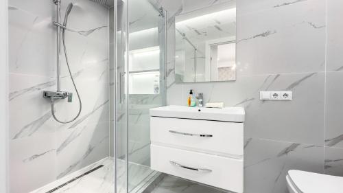 La salle de bains blanche est pourvue d'une douche et d'un lavabo. dans l'établissement Ismail Ultracentral Deluxe Apartaments, à Chişinău