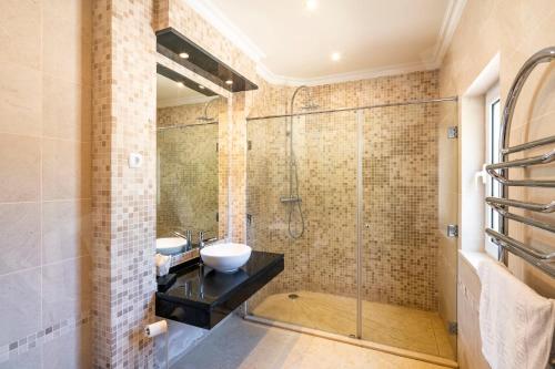 La salle de bains est pourvue d'une douche en verre et d'un lavabo. dans l'établissement Villa Eden, à Carvoeiro