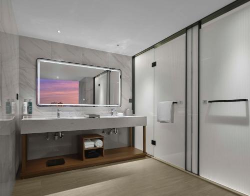 ein Bad mit einem Waschbecken und einem Spiegel in der Unterkunft Hilton Garden Inn Ganzhou Longnan in Longnan