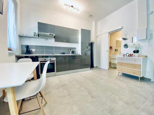 une grande cuisine blanche avec une table et des chaises dans l'établissement Grand studio pour 2 Perpignan Bir Hakeim, à Perpignan
