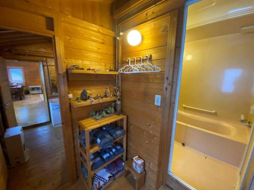 a room with wooden walls and a closet with shelves at Oasis biei in Shibinai