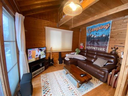 uma sala de estar com um sofá de couro e uma televisão de ecrã plano em Oasis biei em Shibinai