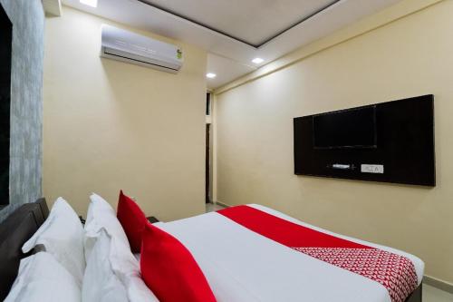 a bedroom with a bed with a television on the wall at Hotel Sunrise in Naroda