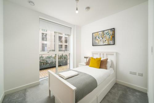 een witte slaapkamer met een bed en een raam bij Madika Homes - Cosy 2 Bed 2 Bath in Colindale London in Colindale