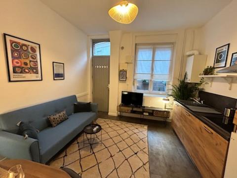 un salon avec un canapé bleu et une cuisine dans l'établissement Maison Lille à 50m du métro, à Lille