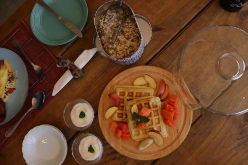 a wooden table with a plate of waffles and fruit at Gemstone Farm in Plettenberg Bay