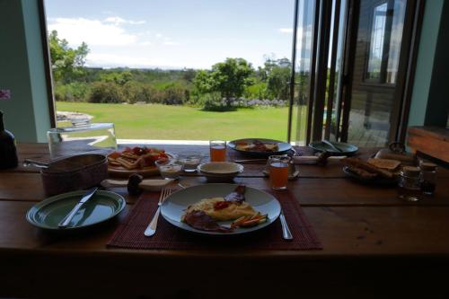 einen Tisch mit Teller mit Lebensmitteln auf einem Tisch mit einem Fenster in der Unterkunft Gemstone Farm in Plettenberg Bay