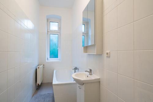 ein weißes Badezimmer mit einem Waschbecken und einem Spiegel in der Unterkunft Apt Volt - Modern, neu, komplett ausgestattet, 4 Einzelbetten, zentral mit Waschmaschine Spülmaschine TV Herd Backofen Mikrowelle in Fürstenwalde