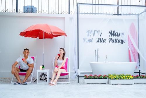 a man and woman sitting in chairs under an umbrella in a bathroom at Home to my heart mare pool villa in Jomtien Beach