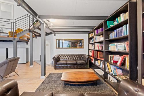 a living room with a leather couch and bookshelves at Big family apartment Berlin Treptower Park in Berlin