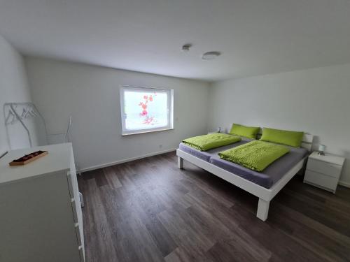Un dormitorio con una cama con almohadas verdes y una ventana en Titel Am Fuße der Rhön, ist es schön, en Bad Kissingen