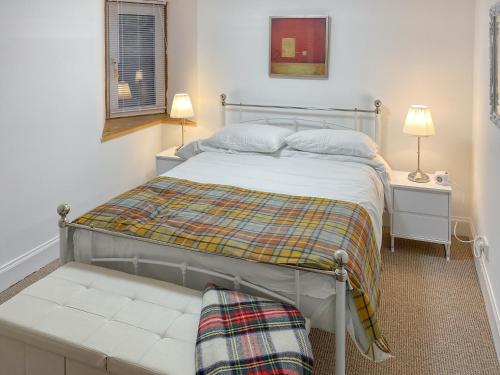 1 dormitorio con cama y banco. en The Thistle, en Auchtermuchty