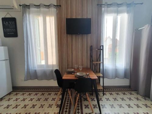 - une salle à manger avec une table et deux fenêtres dans l'établissement Studio confort pour 2 Perpignan Bir Hakeim, à Perpignan