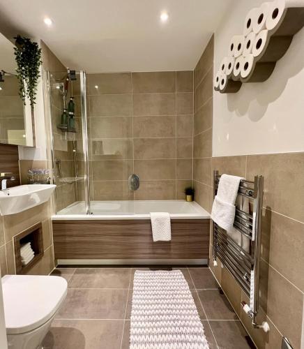a bathroom with a tub and a toilet and a sink at Wembley residency in Brent