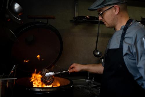 a man in a kitchen cooking food on a grill at Hostal La Cigüeña in Portinatx