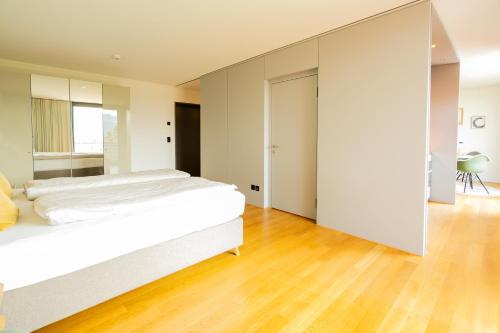 1 dormitorio con 1 cama blanca grande y suelo de madera en Senevita Residenz & Apartments Muri bei Bern, en Berna